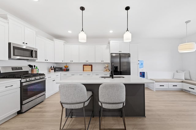 kitchen with appliances with stainless steel finishes, white cabinetry, decorative light fixtures, and sink