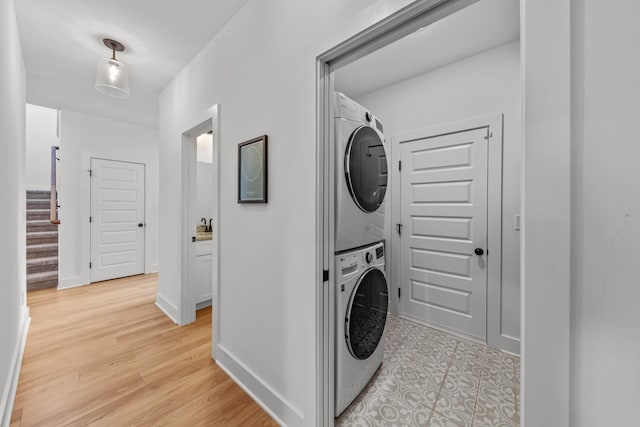 laundry area featuring stacked washer and clothes dryer and light hardwood / wood-style floors