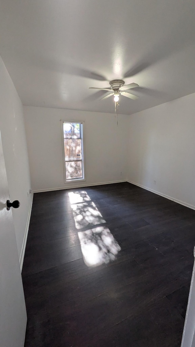 empty room with dark wood-type flooring and ceiling fan