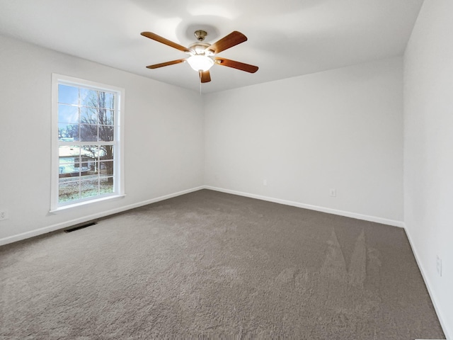 spare room with ceiling fan and dark colored carpet