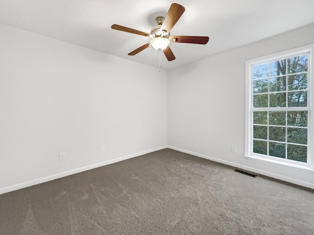 empty room with ceiling fan and dark colored carpet