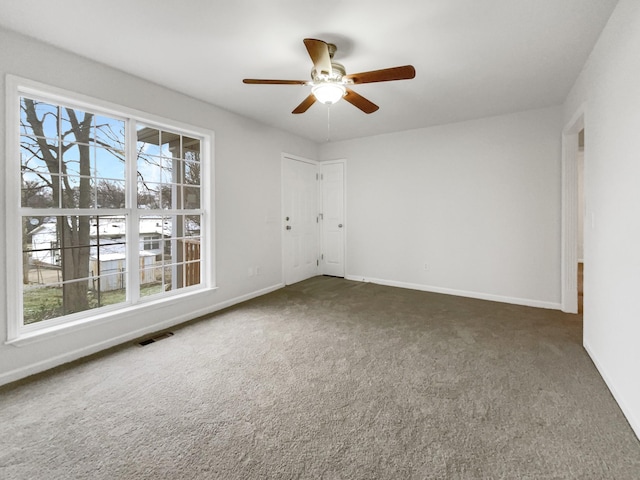 unfurnished room with ceiling fan and dark carpet