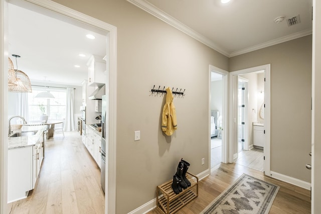 hall with light hardwood / wood-style floors, sink, and crown molding