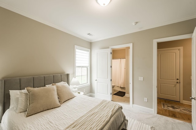 bedroom featuring ensuite bathroom, crown molding, and carpet flooring