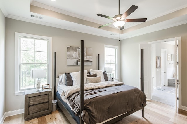 bedroom with ceiling fan, crown molding, light hardwood / wood-style flooring, and a tray ceiling