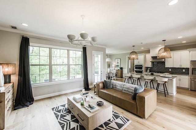 living room with ornamental molding, a chandelier, and light wood-type flooring