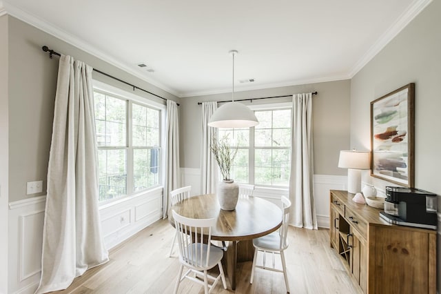 dining room with ornamental molding and light hardwood / wood-style flooring