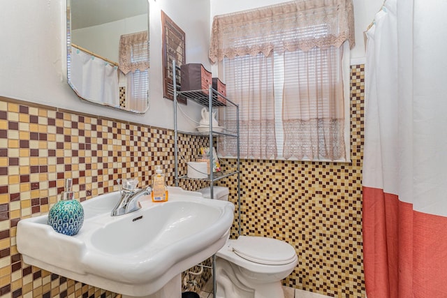 bathroom with a shower with shower curtain, sink, tile walls, and toilet