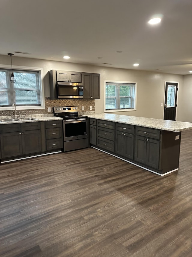 kitchen featuring decorative light fixtures, sink, backsplash, dark hardwood / wood-style flooring, and stainless steel appliances