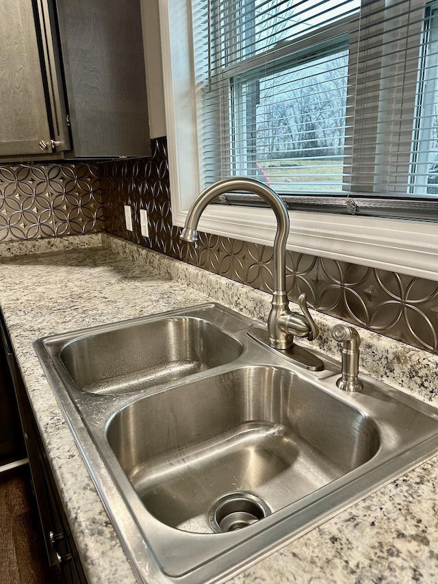 room details with decorative backsplash, sink, and light stone countertops