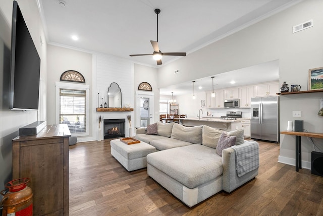 living room with dark wood-type flooring, ornamental molding, and a fireplace