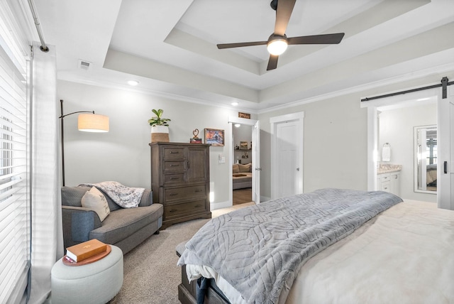 bedroom with ceiling fan, ensuite bath, a tray ceiling, and a barn door