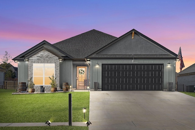 view of front of house with a garage, a lawn, and central AC