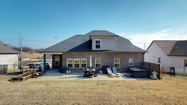 rear view of house featuring a hot tub, a patio area, and a lawn