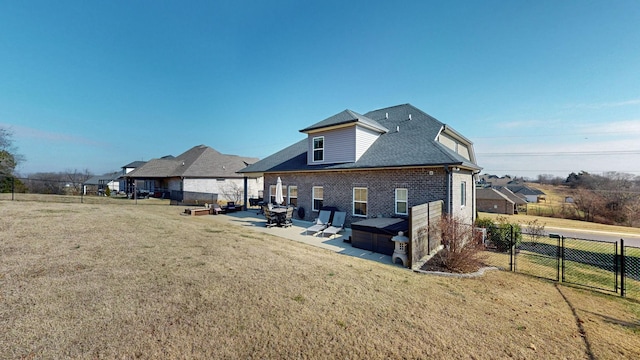 back of house featuring a hot tub, a patio area, and a lawn