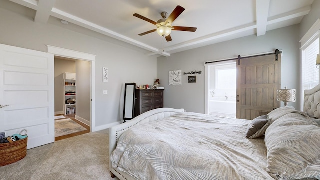 bedroom featuring connected bathroom, beamed ceiling, carpet floors, ceiling fan, and a barn door