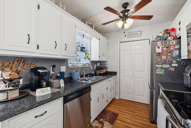 kitchen featuring a textured ceiling, appliances with stainless steel finishes, hardwood / wood-style floors, white cabinetry, and sink