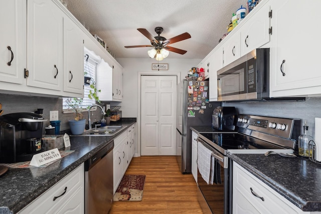 kitchen featuring a textured ceiling, appliances with stainless steel finishes, white cabinets, and sink