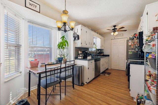 kitchen featuring ceiling fan with notable chandelier, white cabinets, sink, light wood-type flooring, and stainless steel dishwasher