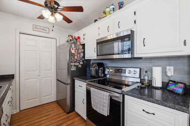 kitchen featuring a textured ceiling, white cabinets, appliances with stainless steel finishes, tasteful backsplash, and hardwood / wood-style flooring