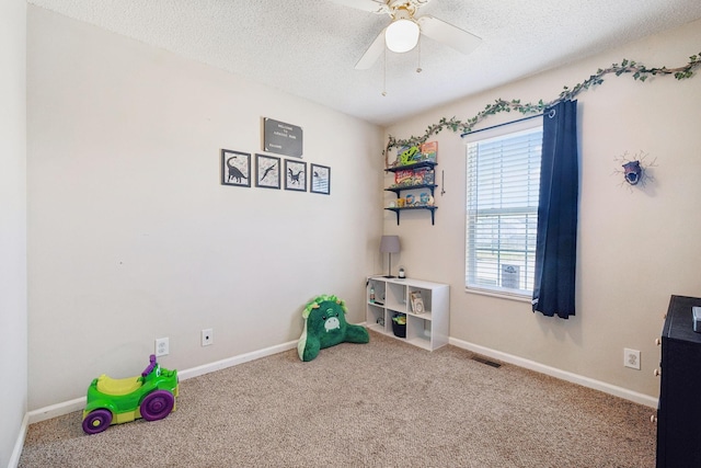 playroom featuring ceiling fan, carpet, and a textured ceiling