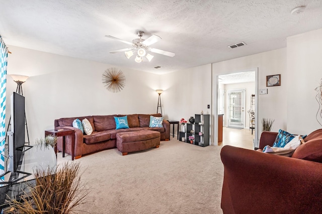 carpeted living room featuring ceiling fan and a textured ceiling