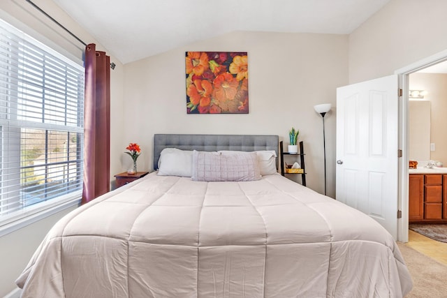 bedroom featuring light colored carpet, multiple windows, ensuite bathroom, and vaulted ceiling