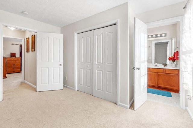 carpeted bedroom with ensuite bathroom and a closet