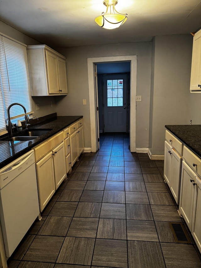 kitchen featuring white dishwasher, dark stone countertops, white cabinets, and sink