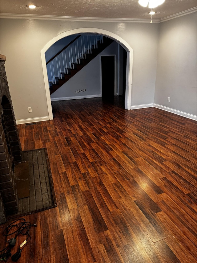 unfurnished living room featuring a textured ceiling, ornamental molding, a fireplace, and dark hardwood / wood-style floors