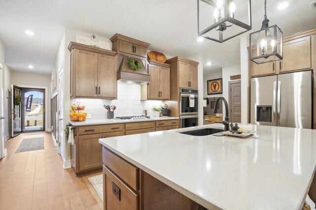 kitchen with stainless steel appliances, light countertops, a sink, and a large island