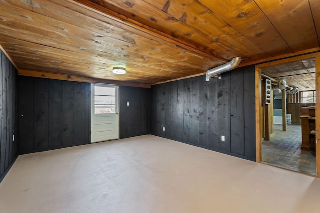 additional living space with wooden ceiling, a wealth of natural light, wooden walls, and concrete floors