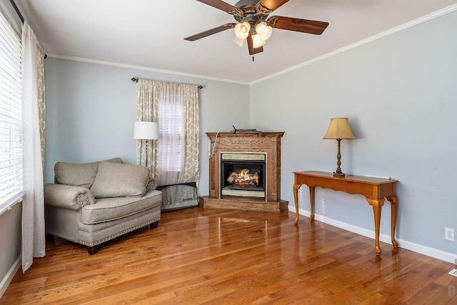 living area with a wealth of natural light, crown molding, and hardwood / wood-style flooring