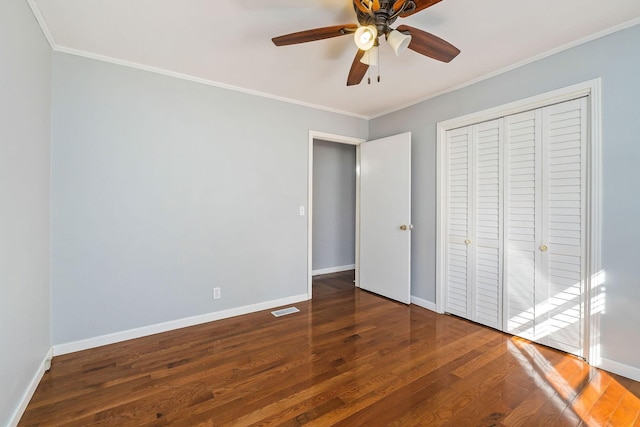 unfurnished bedroom featuring ceiling fan, a closet, dark hardwood / wood-style floors, and ornamental molding