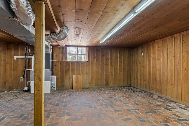 basement featuring wooden ceiling, heating unit, and wood walls