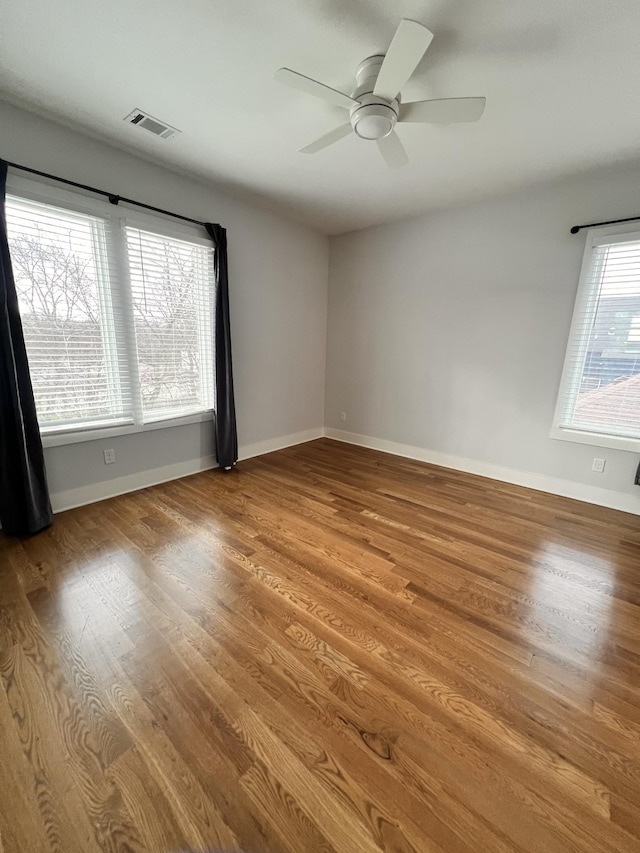 empty room featuring ceiling fan, plenty of natural light, and hardwood / wood-style flooring