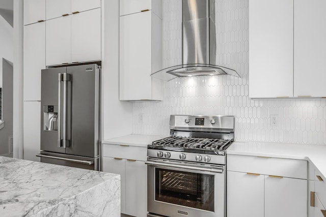 kitchen with decorative backsplash, white cabinets, stainless steel appliances, and wall chimney exhaust hood