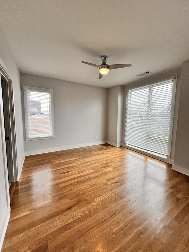 empty room with ceiling fan, a healthy amount of sunlight, and light hardwood / wood-style floors