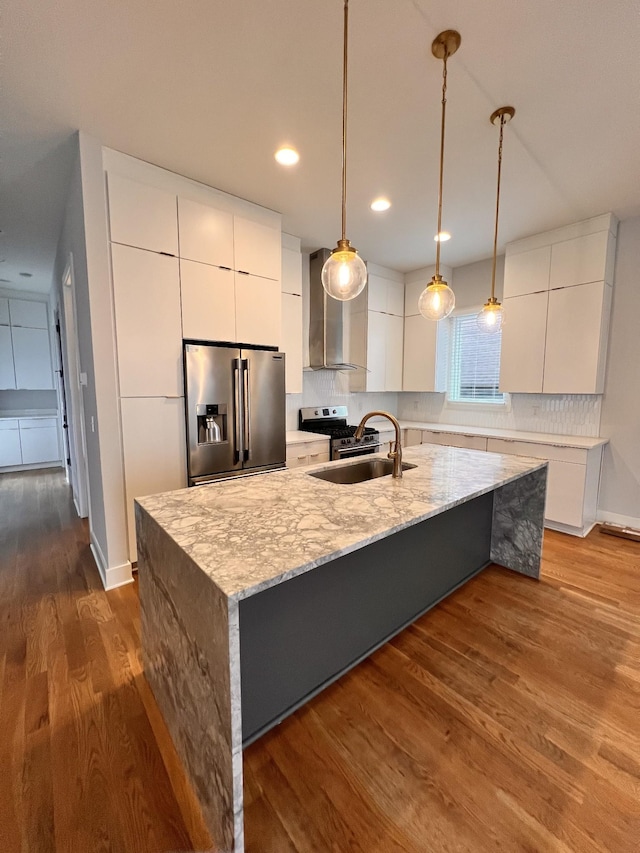 kitchen with appliances with stainless steel finishes, backsplash, white cabinetry, and wall chimney range hood