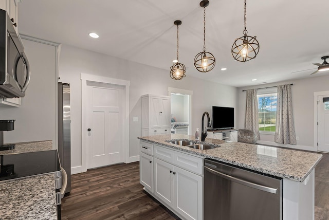 kitchen with appliances with stainless steel finishes, white cabinetry, an island with sink, sink, and hanging light fixtures