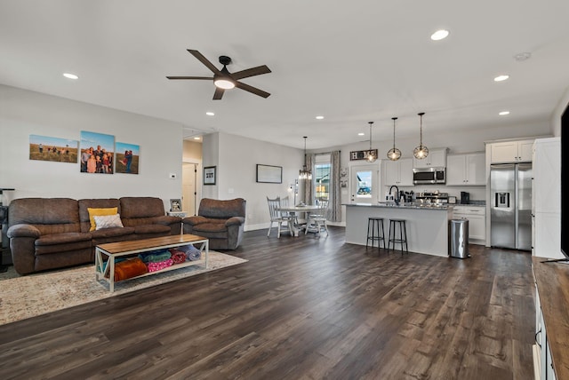 living room with ceiling fan, dark hardwood / wood-style flooring, and sink