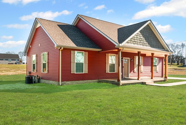 rear view of property featuring covered porch, central AC unit, and a lawn