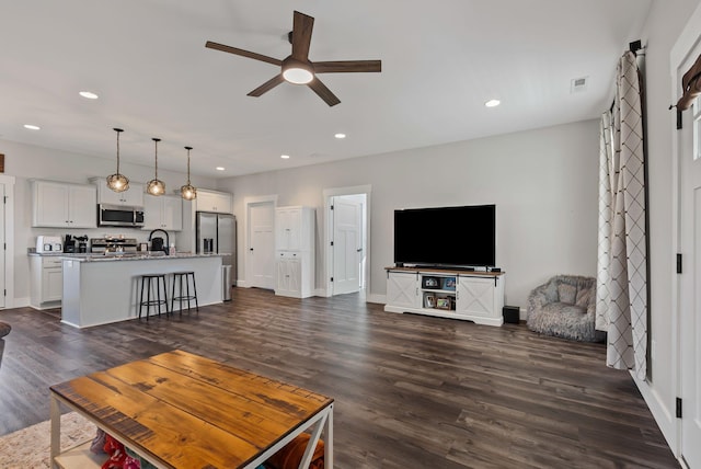 living room with ceiling fan, dark hardwood / wood-style floors, and sink