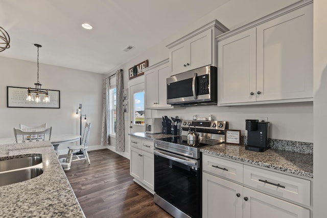 kitchen featuring appliances with stainless steel finishes, decorative light fixtures, dark hardwood / wood-style flooring, light stone countertops, and white cabinets