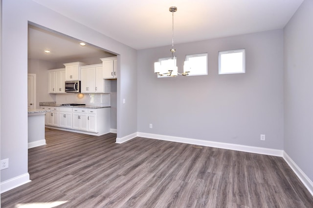 kitchen featuring white cabinetry, tasteful backsplash, dark wood-type flooring, pendant lighting, and light stone counters