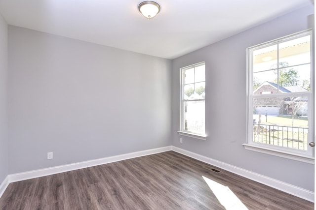 empty room with dark wood-type flooring and a wealth of natural light