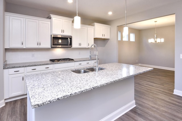 kitchen featuring decorative backsplash, sink, white cabinetry, appliances with stainless steel finishes, and an island with sink