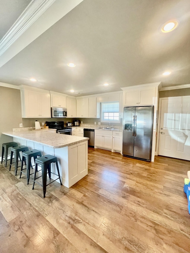 kitchen featuring kitchen peninsula, sink, white cabinetry, light wood-type flooring, and stainless steel appliances