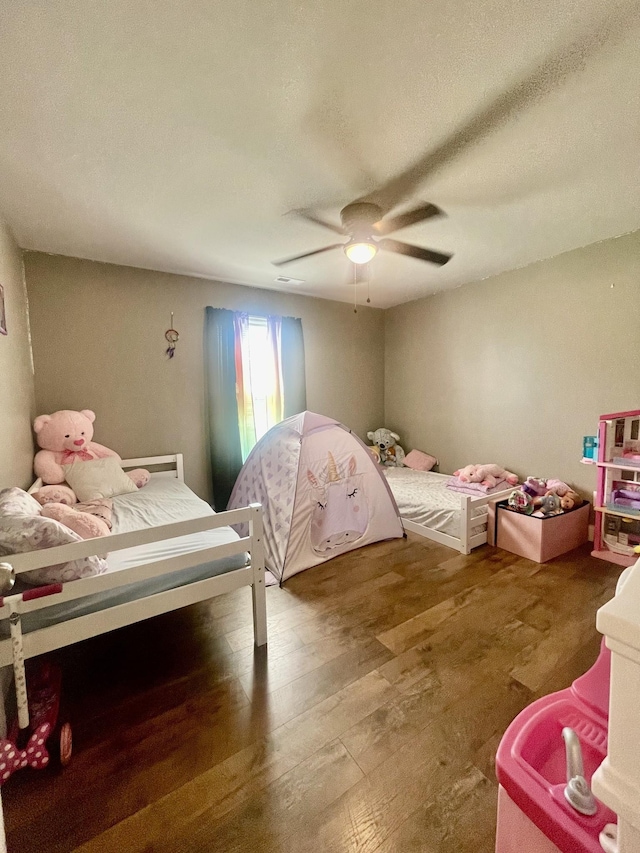 bedroom featuring ceiling fan, hardwood / wood-style floors, and a textured ceiling