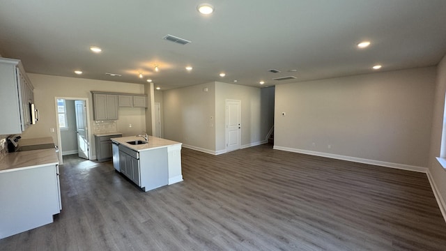 kitchen featuring sink, range, dark hardwood / wood-style floors, a kitchen island with sink, and decorative backsplash